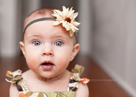 Toddler looking at camera with white flower bow