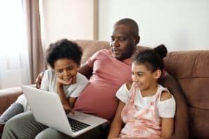parent and children on couch looking at computer