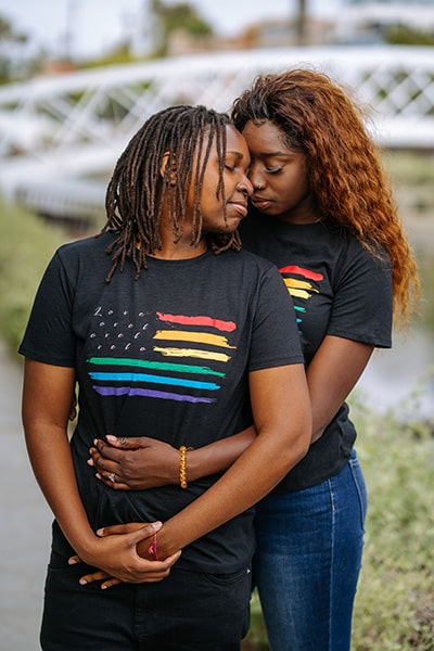 two women with rainbow flag shirts embracing