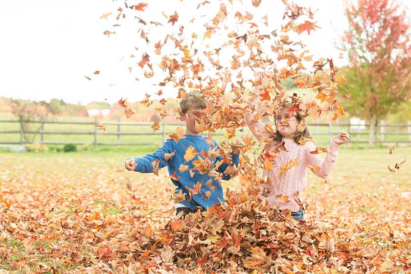 two children throwing leaves in the air