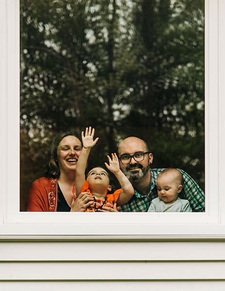 family posed behind window with tree reflection