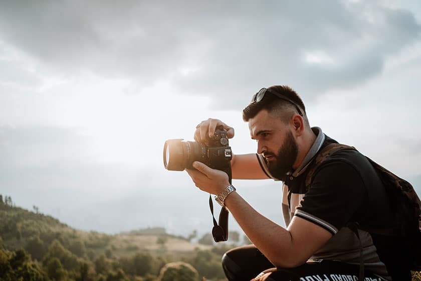 man taking picture with camera in the mountains