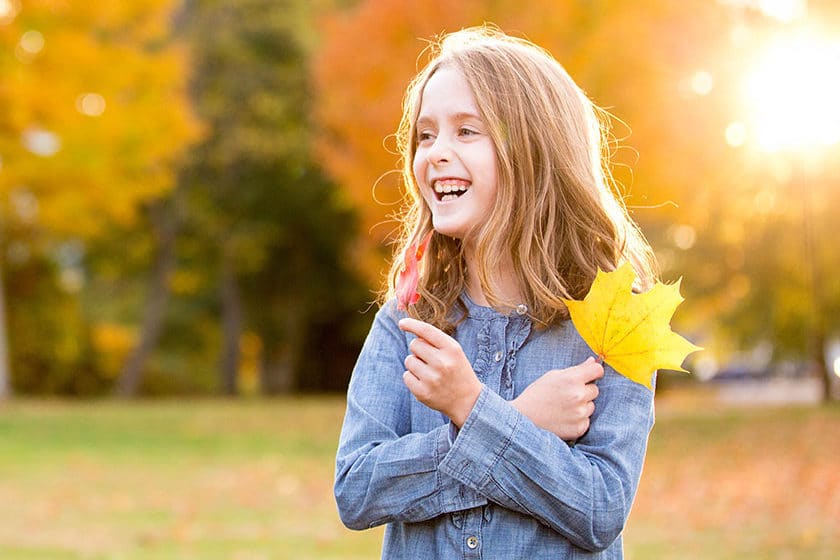 girl holding one red leaf and one yellow leaf