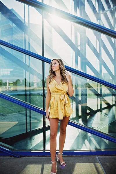 teenage girl posed in front of a glass and metal building