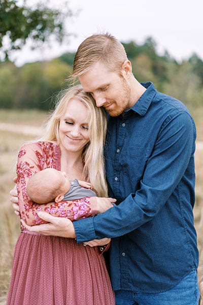 couple helping each other hold newborn baby