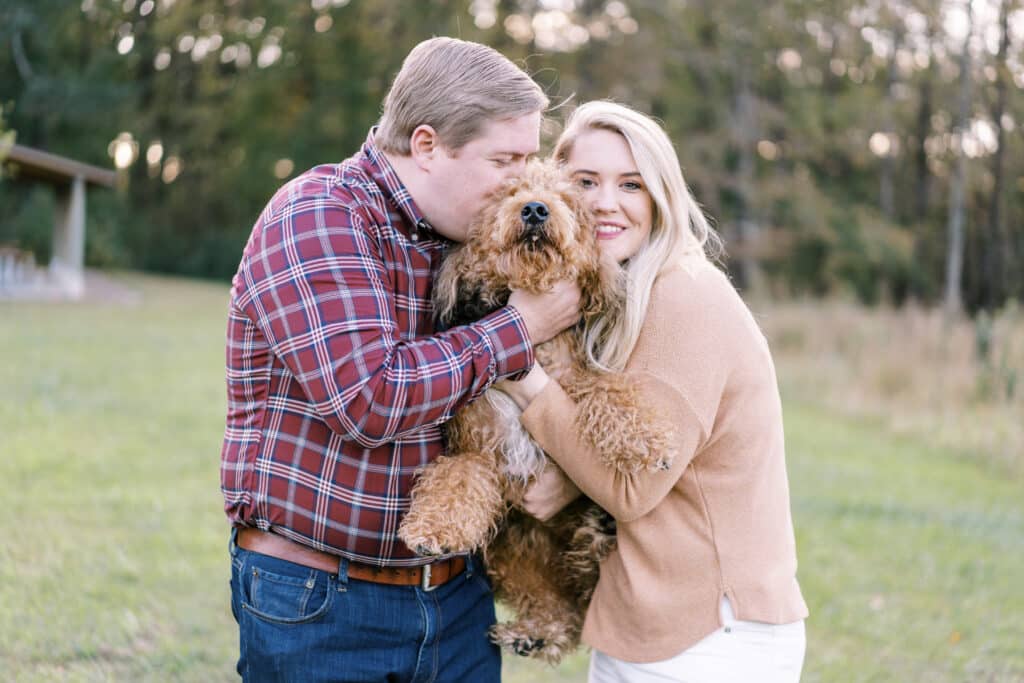 man and woman holding golden doodle dog