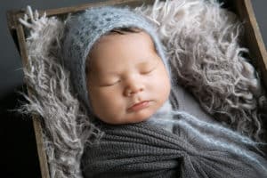 sleeping newborn swaddled in grey blankets