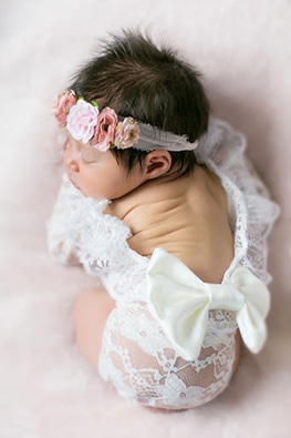 newborn wearing lace onesie with bow
