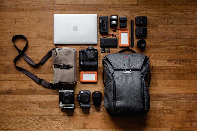 flat lay with laptop, camera bodies, camera lenses, gear bags, and related equipment