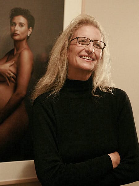 portrait of Annie Leibovitz in front of her famous Demi Moore photograph