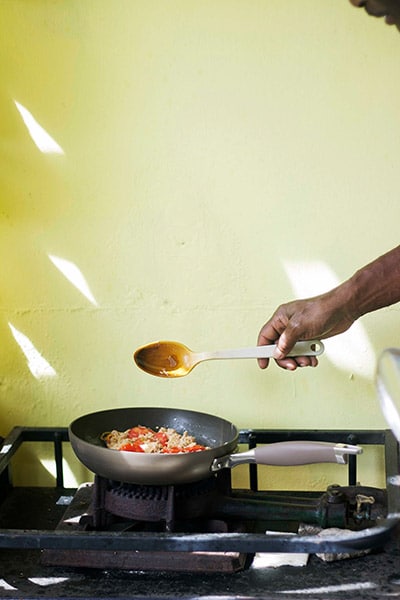 burner with pan of cooking food in front of a yellow wall