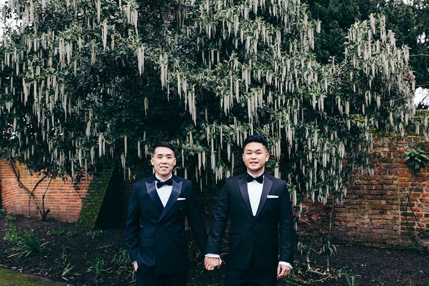portrait of gay couple holding hands on their wedding day