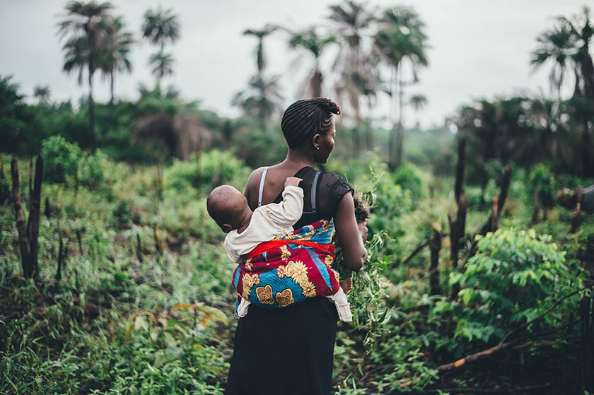mother in the forest in sierra leone carrying baby on her back