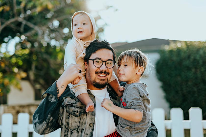 portrait of asian man holding two children and smiling at camera