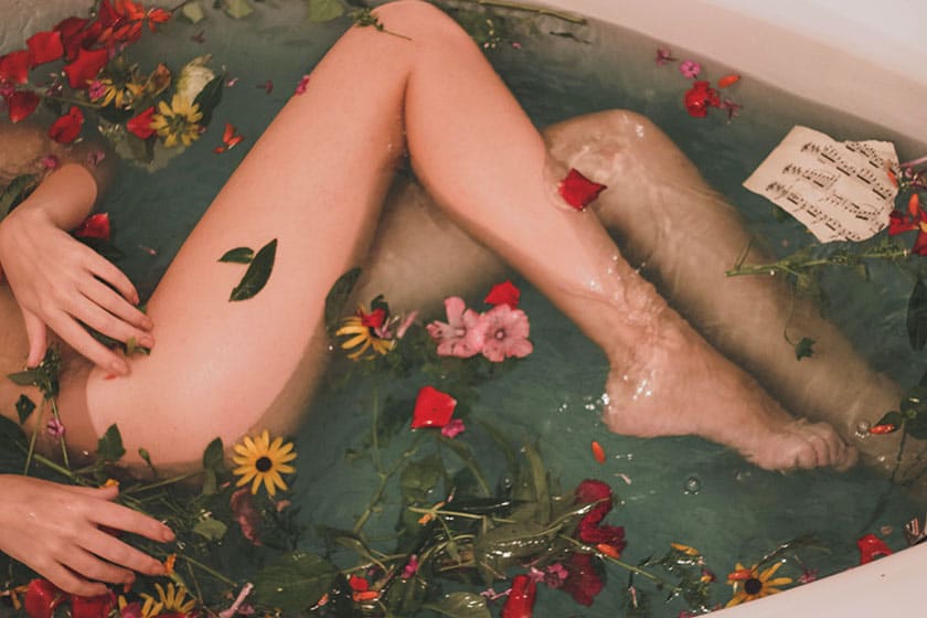 boudoir photography of a woman in a bathtub with flowers floating in the water