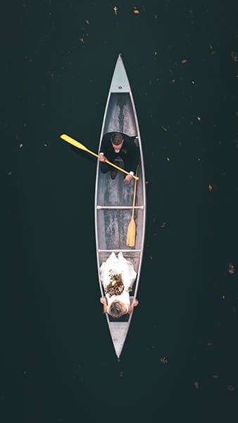 overhead wedding portrait of bride and groom rowing a canoe in the water  