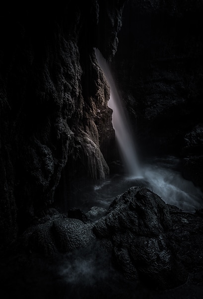 low-key image of waterfall and rocky cliffs with deep shadows
