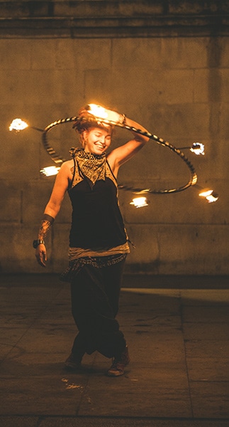 street performer swinging a hula hoop with flaming sticks attached