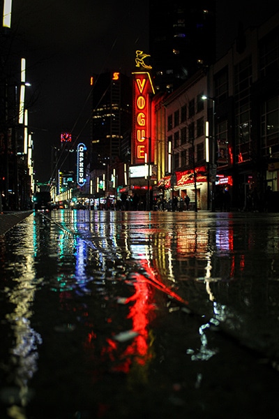 neon street signs reflecting on wet streets at night