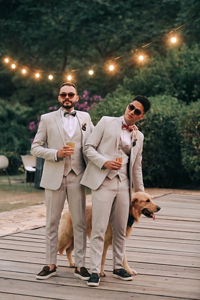 two grooms posing with their dog at their wedding