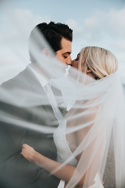 Bride and Groom kissing behind veil