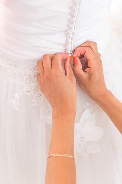 buttoning the back of a bridal gown