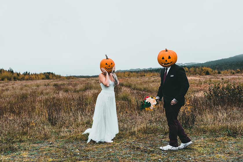 bride and groom with pumpkins on their heads