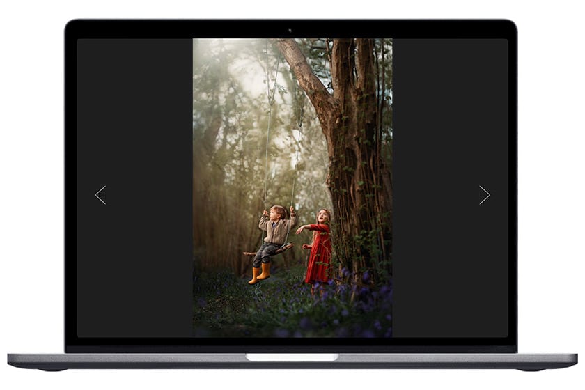 image of boy and girl using a swing in the woods displayed on a laptop screen