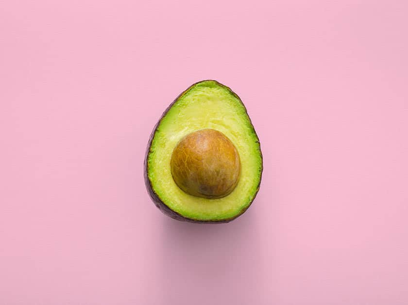 avocado sliced in half on pink surface still life