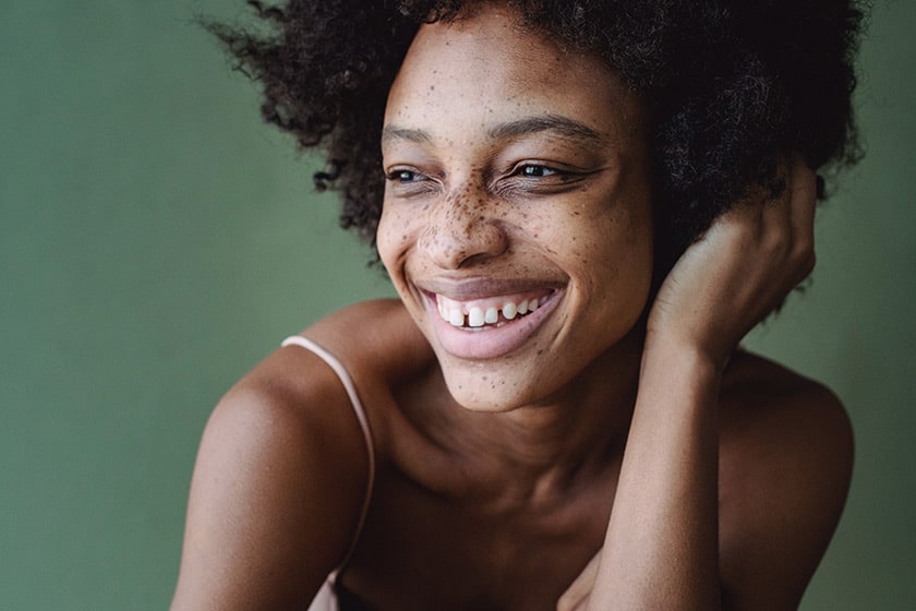 headshot of black woman with freckles smiling and looking to the left