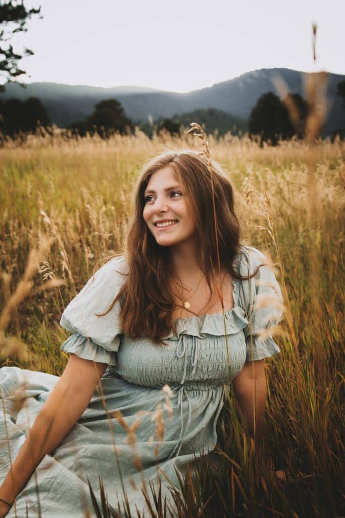 senior girl sitting in a field of tall grass