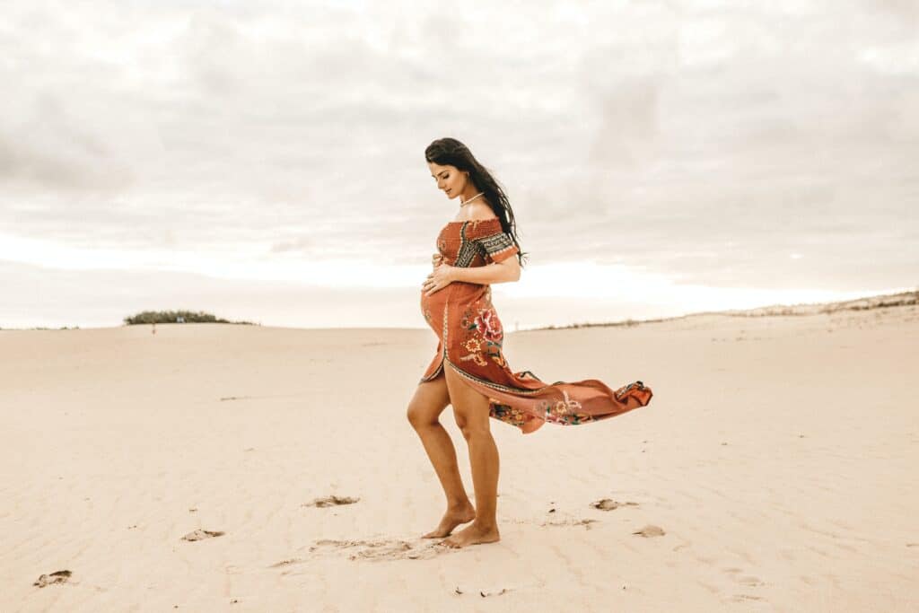 woman in flowing rust dress standing in sand dunes