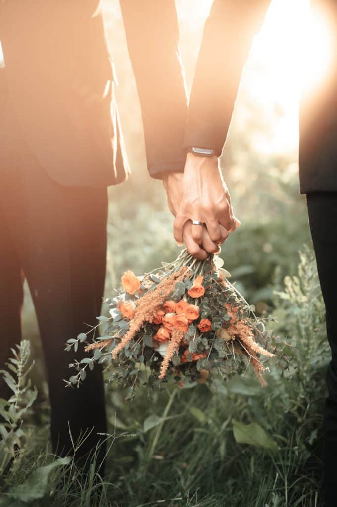 two grooms holding hands and a wedding bouquet