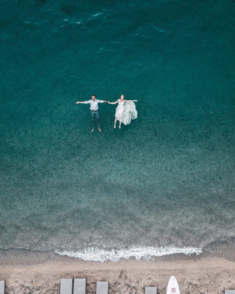wedding couple floating in ocean photographed by drone camera