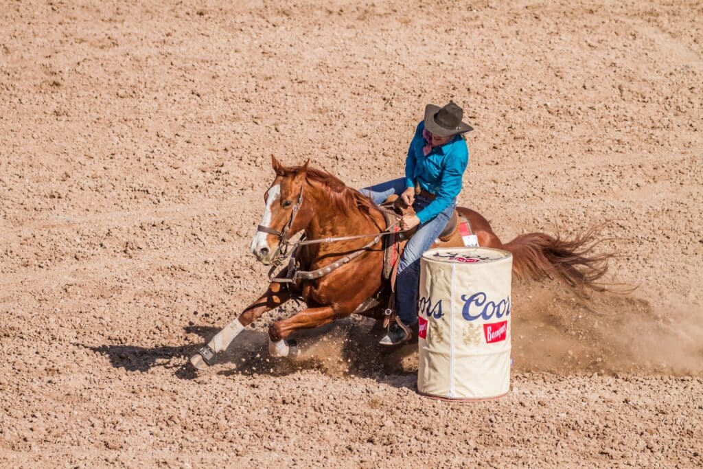 person riding horse in western barrel racing competition