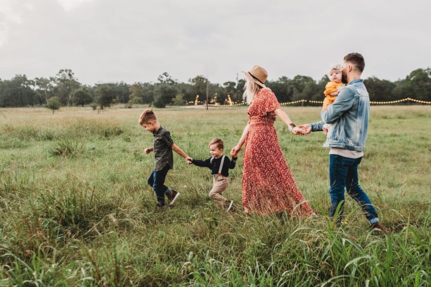 family holding hands and following each other across field
