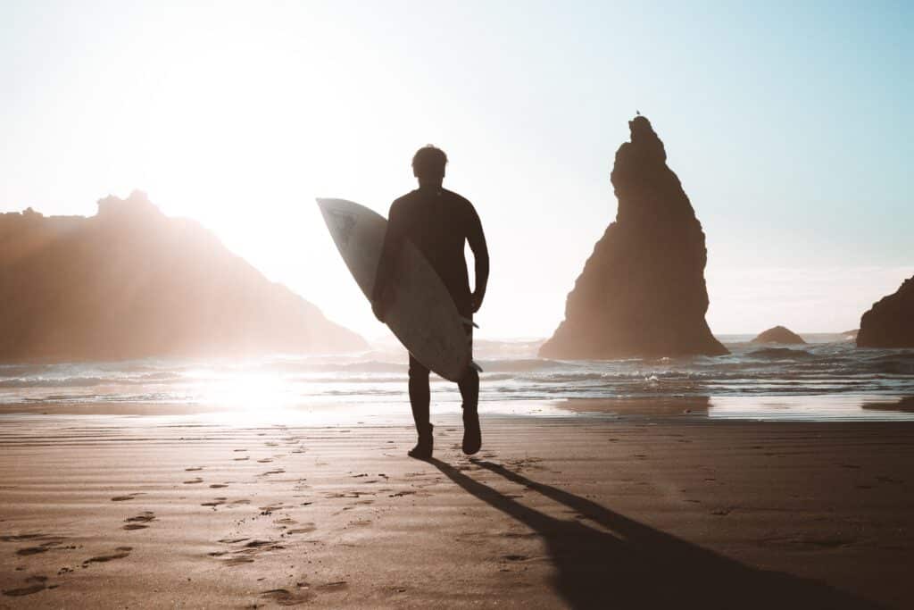 silhouette of surfer carrying board at sunrise