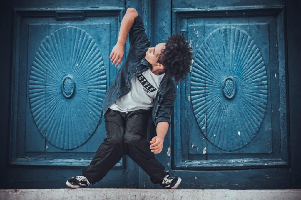 male dancer performing street style moves in front of two blue wooden doors