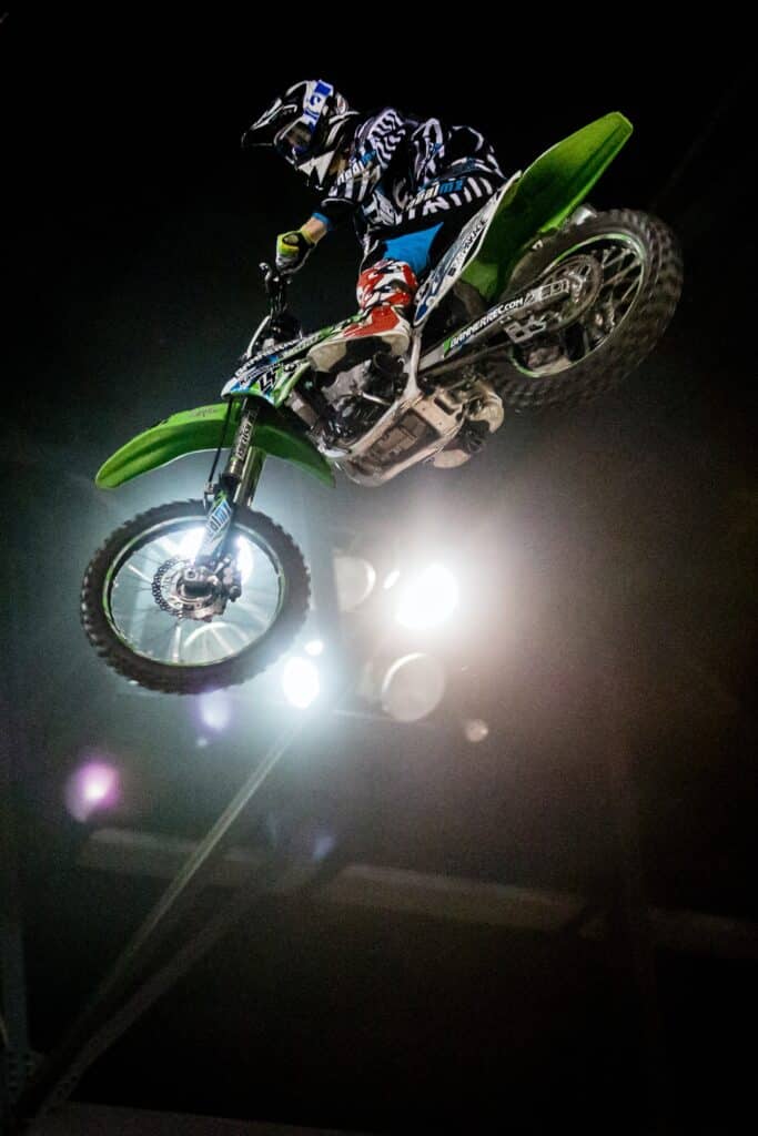 night photography of a rider on a green bike showcasing freestyle motocross