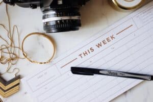 undated planner page with a black sharpie pen and a vintage camera on a marble tabletop