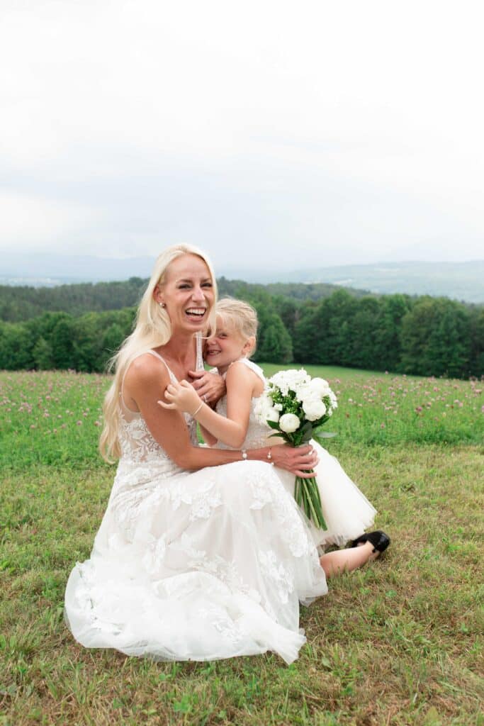 Wild Orchard Studios bride flowergirl Wedding portrait in a grassy field surrounded by trees and distant mountains