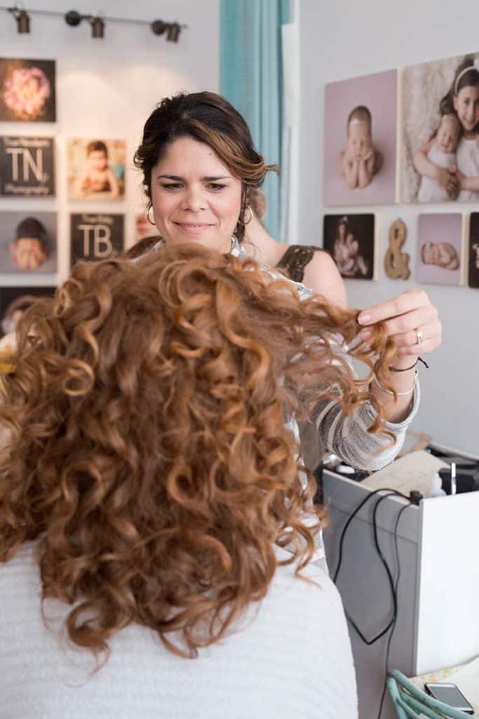 hairdresser styling curly redhead for photoshoot