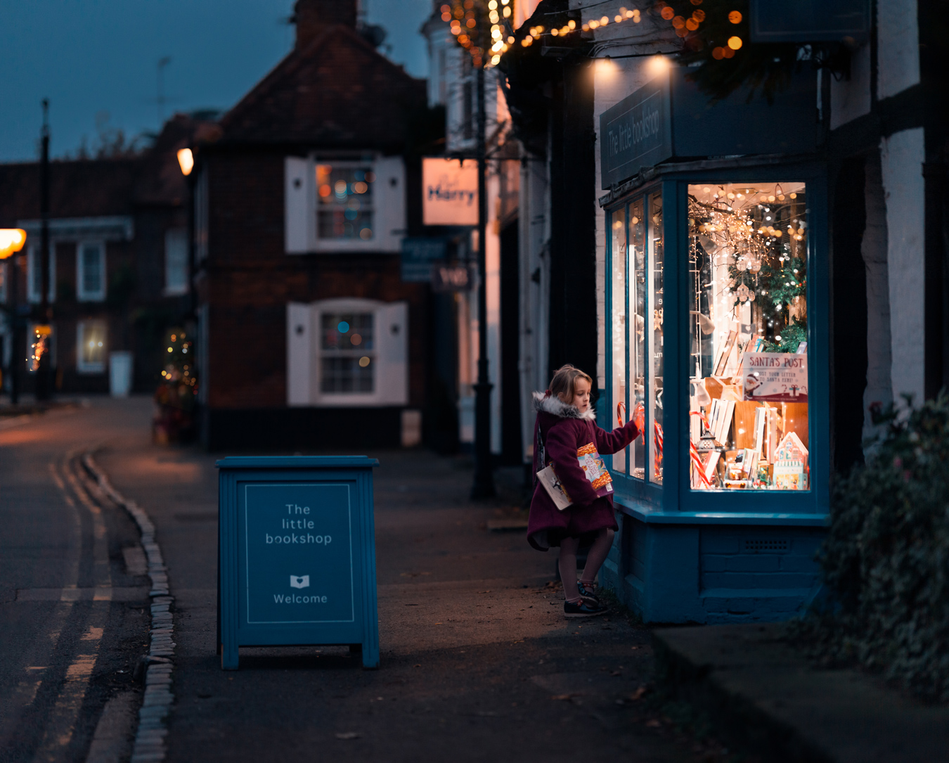 Girl looking at a Christmas-decorated bookstore window at night