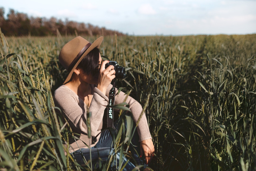 woman sitting in grass looking through camera1080x720v2
