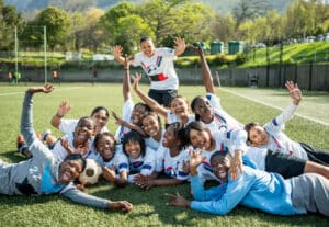 teen girls soccer team doing a fun pose laying on field together