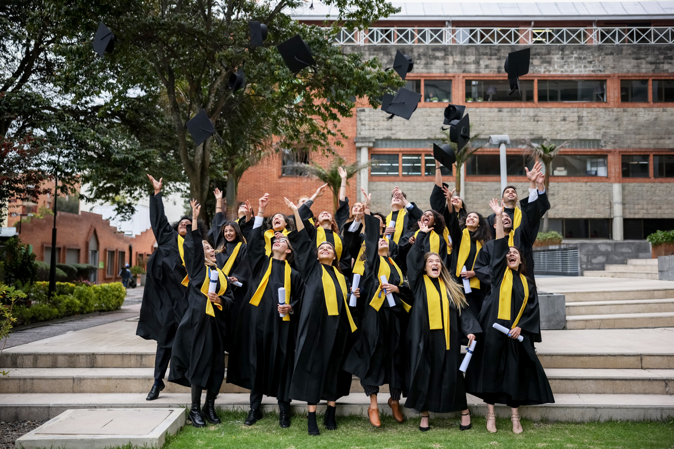 graduates group portrait outdoors throwing caps in air