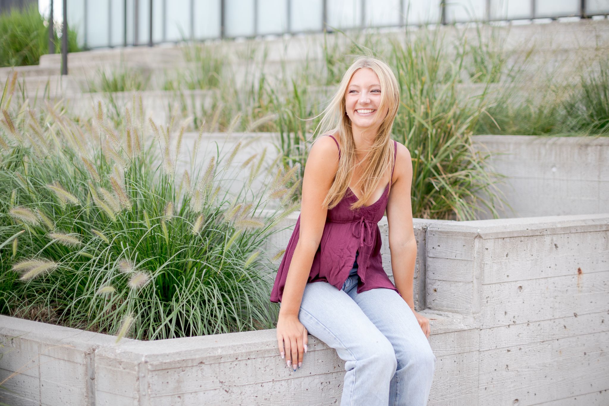 Smiling Woman Sitting Among Ornamental Grasses in an Outdoor Garden
