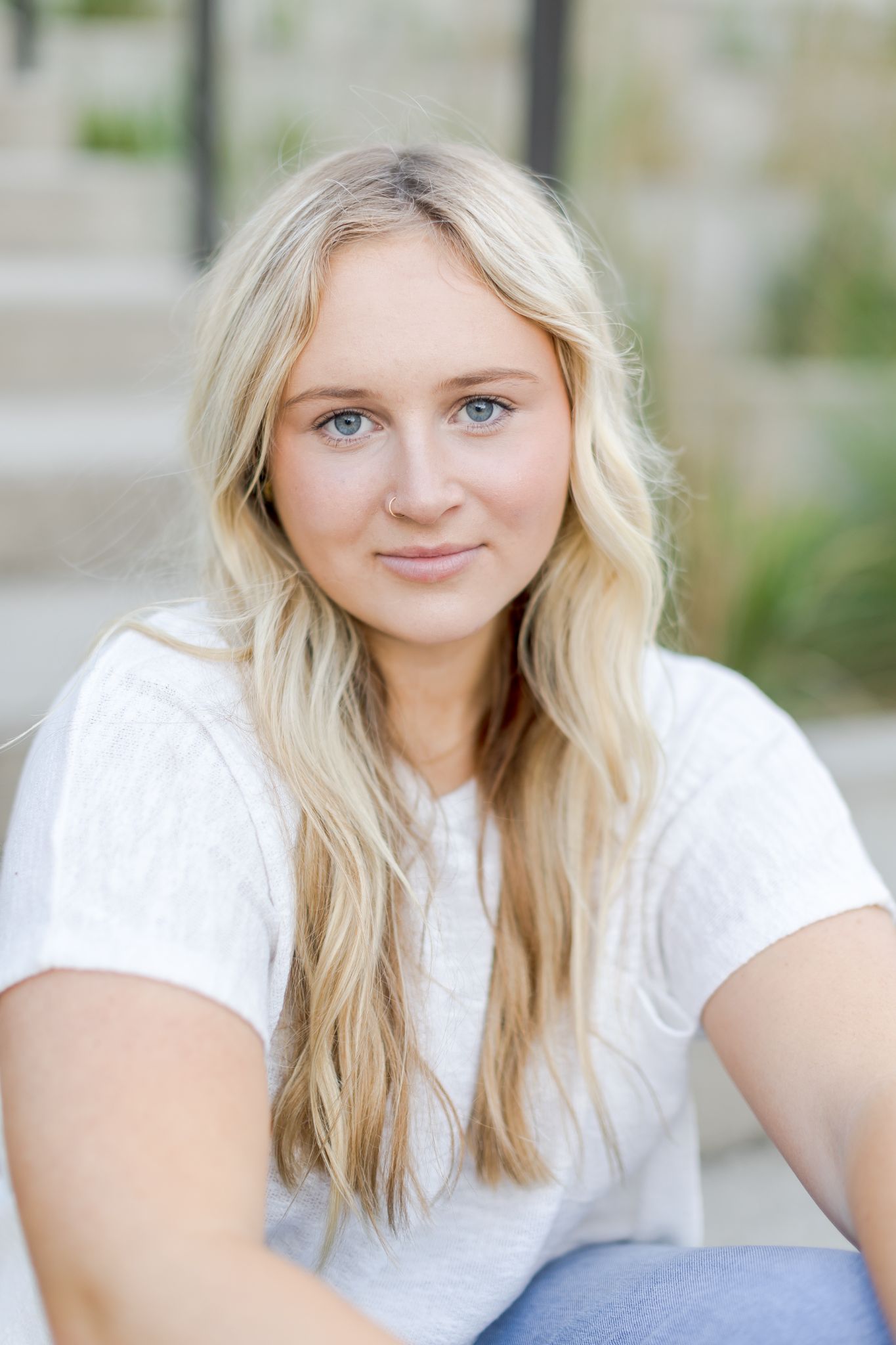 Blonde woman with blue eyes smiling gently in an outdoor portrait