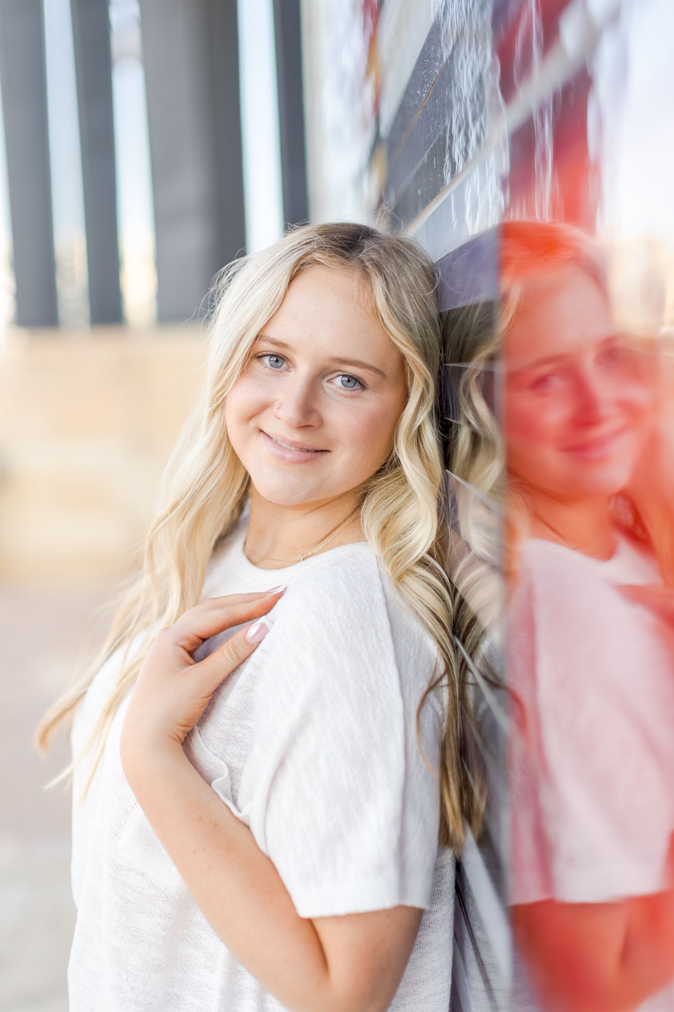 Smiling blonde woman posing beside a colorful reflective glass wall