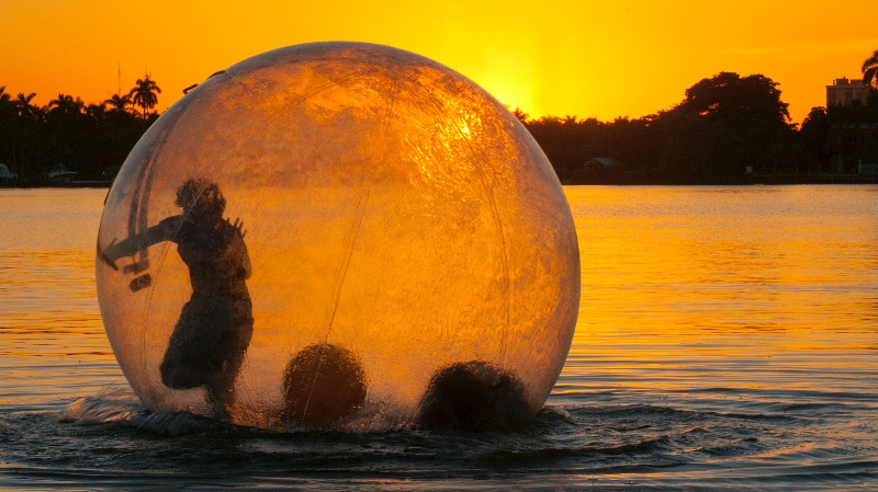 lake photo at sunset of person running in hamster ball